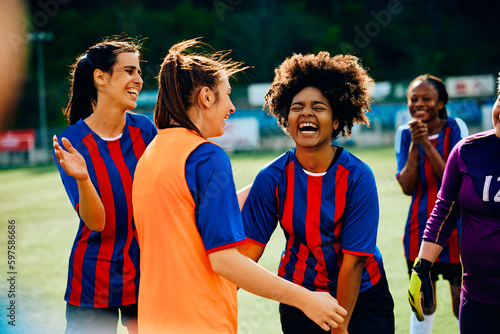 Cheerful black soccer player has fun with her teammates after successful match at stadium. photo