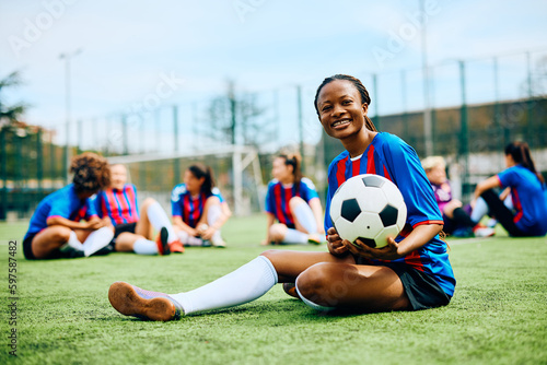 Happy African American female player on soccer training at stadium and looking at camera. photo