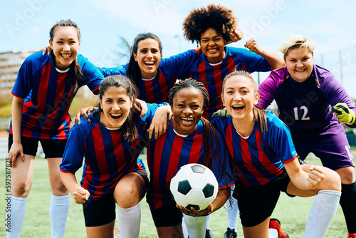 Cheerful female soccer players after winning match at stadium looking at camera. © Drazen