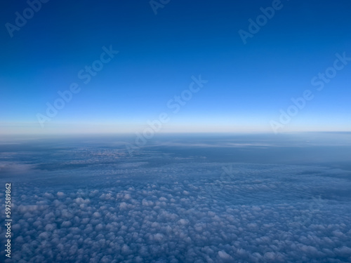Airplane view of white cumulus clouds on turquoise horizon © Nadtochiy