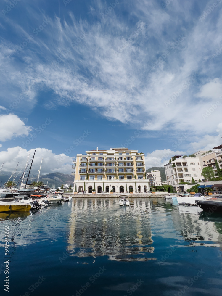 Hotel Regent on the shore of the marina against the background of a cloudy sky. Porto, Montenegro