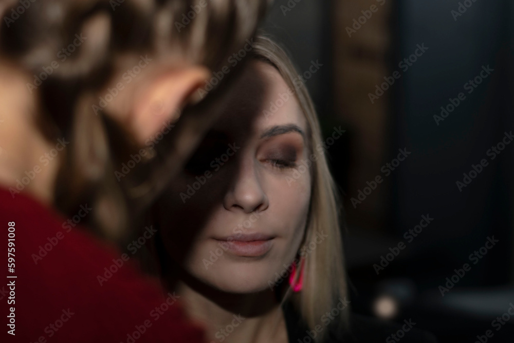 Makeup artist makes a professional evening make-up for a beautiful blonde woman. Creates a contour of the cheekbones with a brush, on the face Concept. Beauty saloon. Close-up Makeup artist makes a professional evening make-up for a beautiful blonde woman. Creates a contour of the cheekbones with a brush, on the face Concept. Beauty saloon. Close-up
