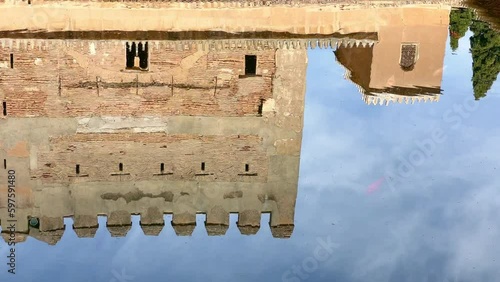Comares Palace and Tower from the Court of Myrtles reflected in the yard pool, Nasrid Palace, Alhambra, Granada, Spain. Rippled water surface 4K footage.