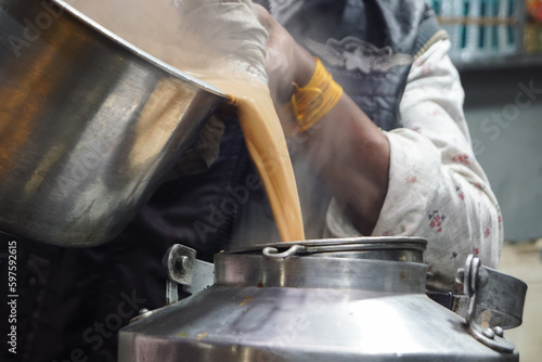 Pouring tea into Tea can. Traditional Indian Kadak Chai, Indian Garam Chaai pouring into cans, copy space.