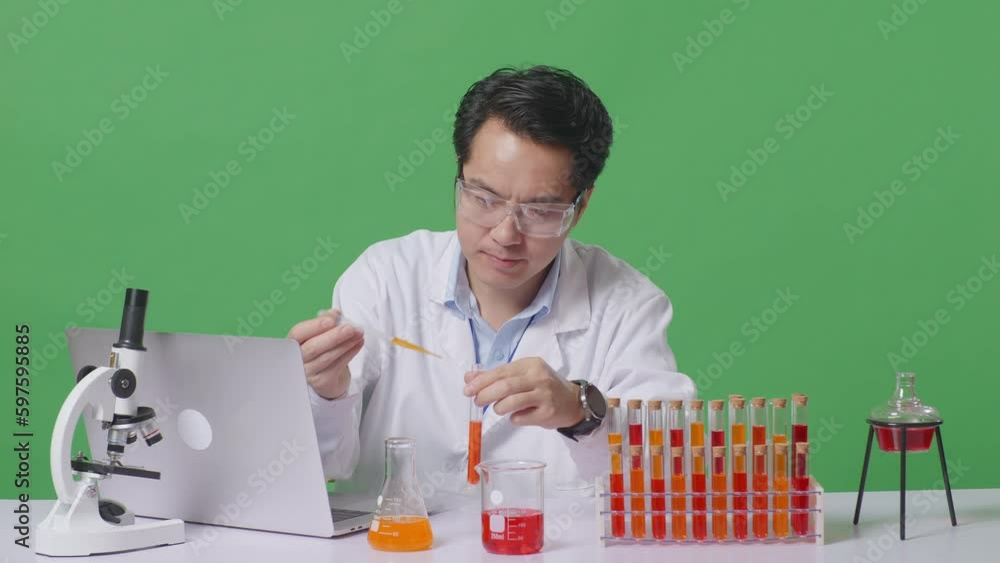 Asian Man Scientist Making Experiment With Test Tube And Typing On A
