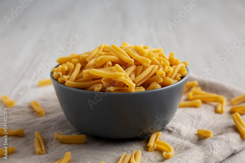 Homemade Raw Organic Caserecce Pasta in a Bowl on a white wooden background, low angle view.