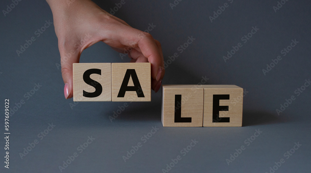 Naklejka premium Sale symbol. Concept word Sale on wooden cubes. Businessman hand. Beautiful grey background. Business and Sale concept. Copy space.
