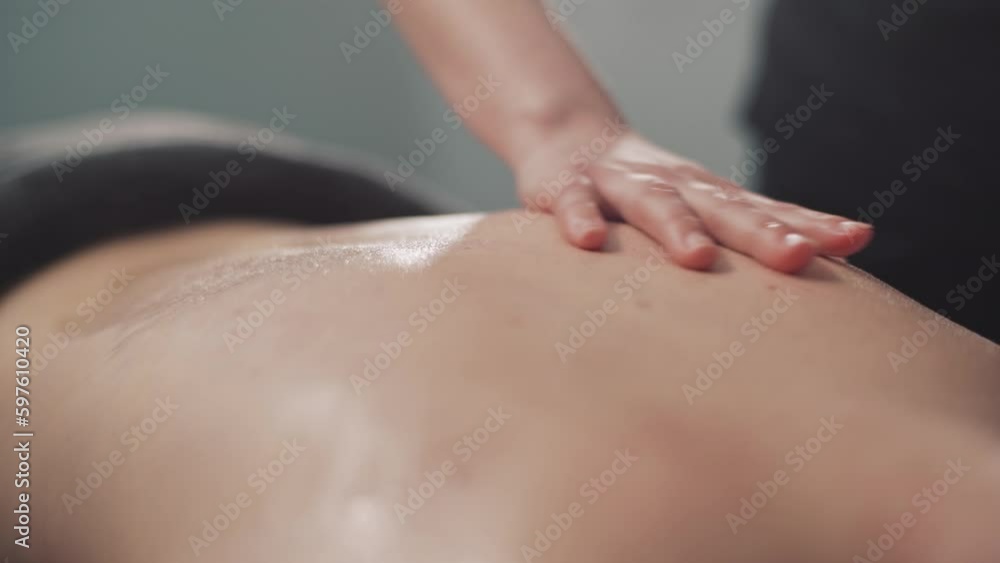 Young woman in spa salon. The hands of the masseur are massaging the woman's back with massage oil. Relaxation, stress relief body in the health center. Young woman in spa salon. The hands of the masseur are massaging the woman's back with massage oil. Relaxation, stress relief body in the health center.