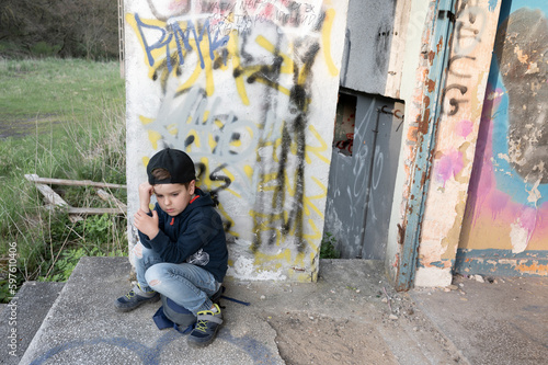 Upset little boy sitting near an abandoned building. Kid's problems. © Iryna Burmii