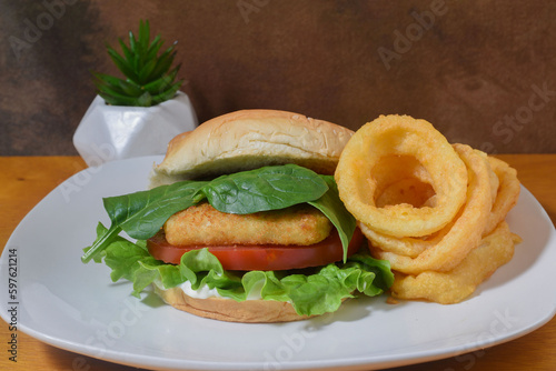 fish sandwich top with spinach and a side of onion rings