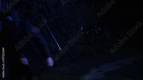 Thief in a mask carries a stolen TV late at night, is caught by the police with flashing lights, runs away, concept of security and violation of the law