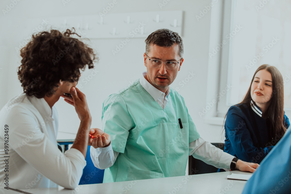 Obraz premium A group of multiethnic medical professionals including doctors, surgeons, and nurses are gathered in a hospital setting discussing patient care and using modern technology to address challenges in
