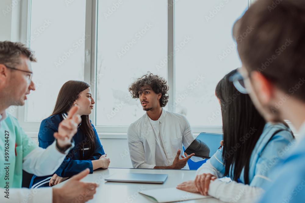 Fototapeta premium A group of multiethnic medical professionals including doctors, surgeons, and nurses are gathered in a hospital setting discussing patient care and using modern technology to address challenges in