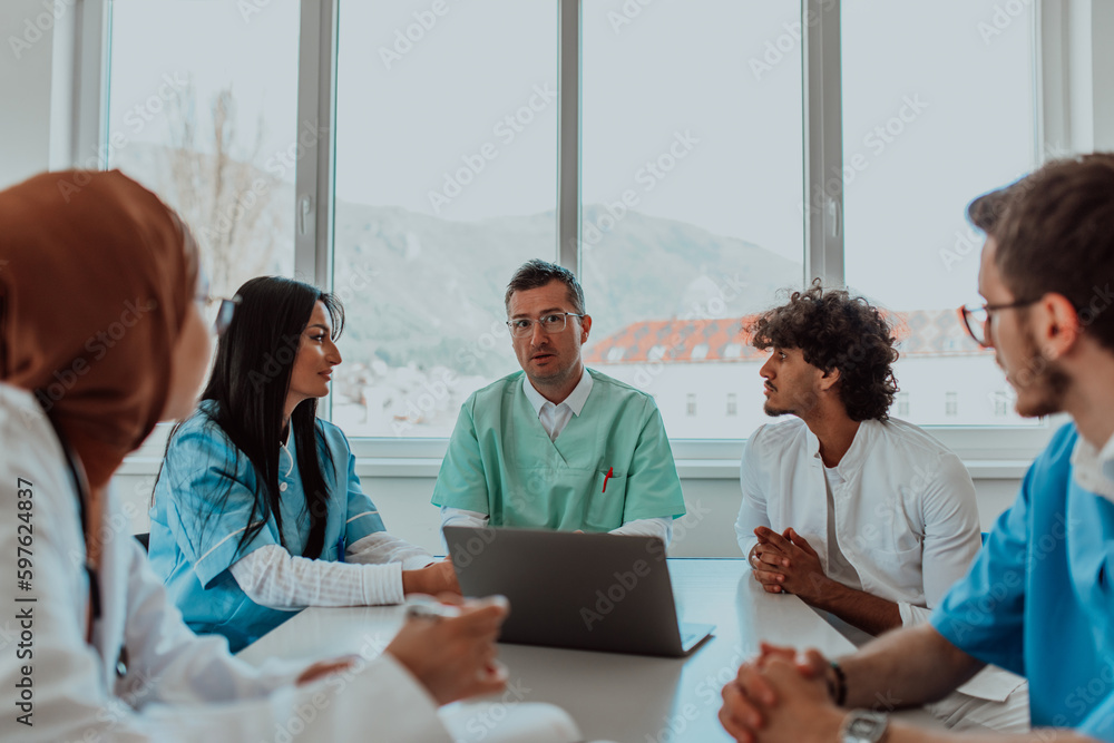 A group of multiethnic medical professionals including doctors, surgeons, and nurses are gathered in a hospital setting discussing patient care and using modern technology to address challenges in - obrazy, fototapety, plakaty 