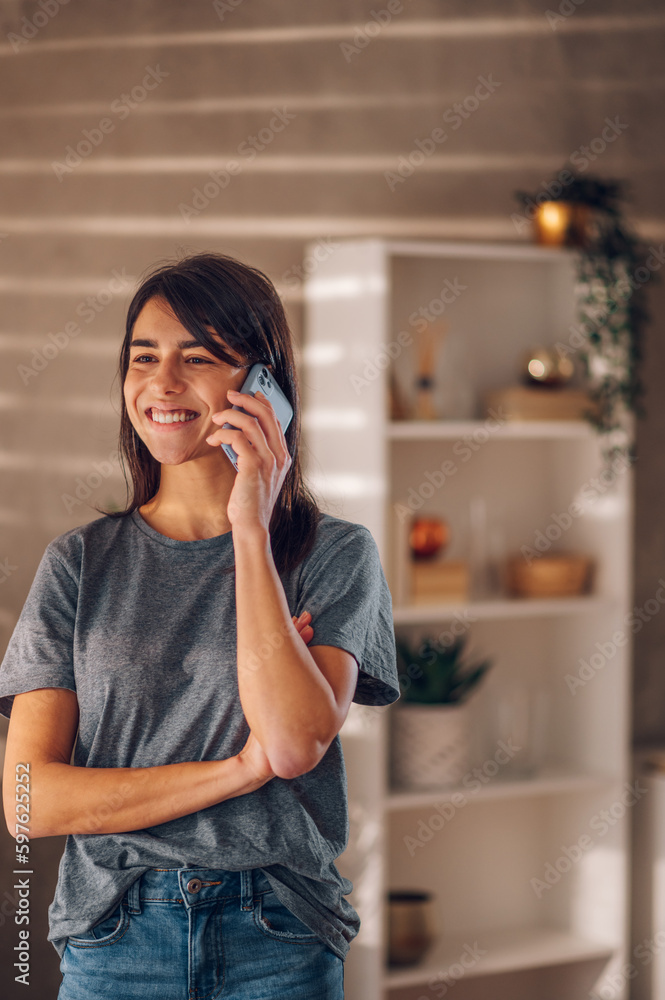 Smiling young woman looking into the distance while talking on the cell phone. Smiling young woman looking into the distance while talking on the cell phone.
