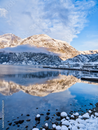 Waterfront buildings in Eidfjord village and mountains at sunset during winter on Hardangerfjord, Norway