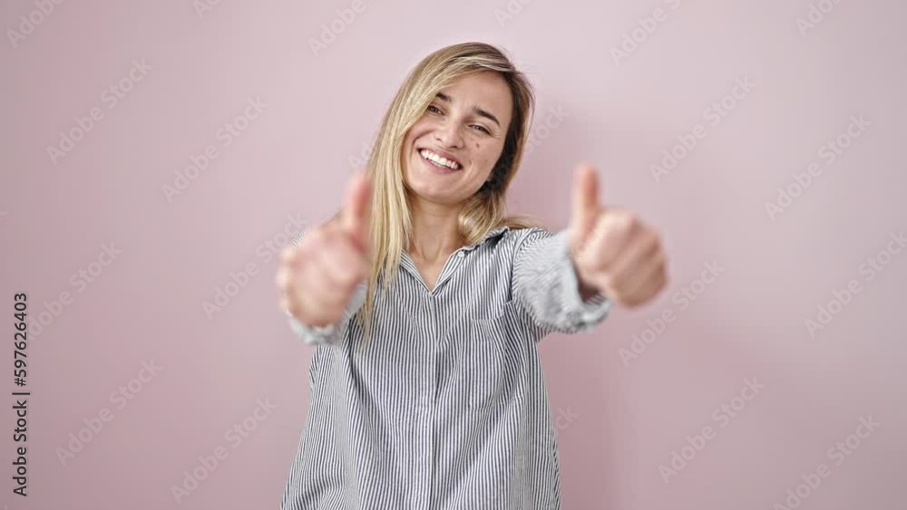 Young blonde woman smiling with thumbs up over isolated pink background Young blonde woman smiling with thumbs up over isolated pink background