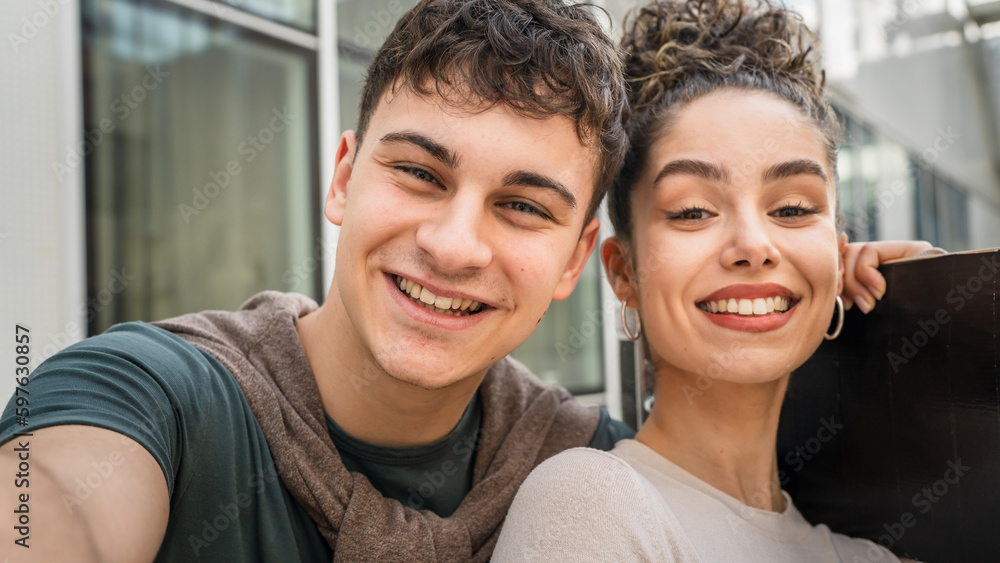 Young man and woman teenager couple take selfies by modern building Young man and woman teenager couple take selfies by modern building