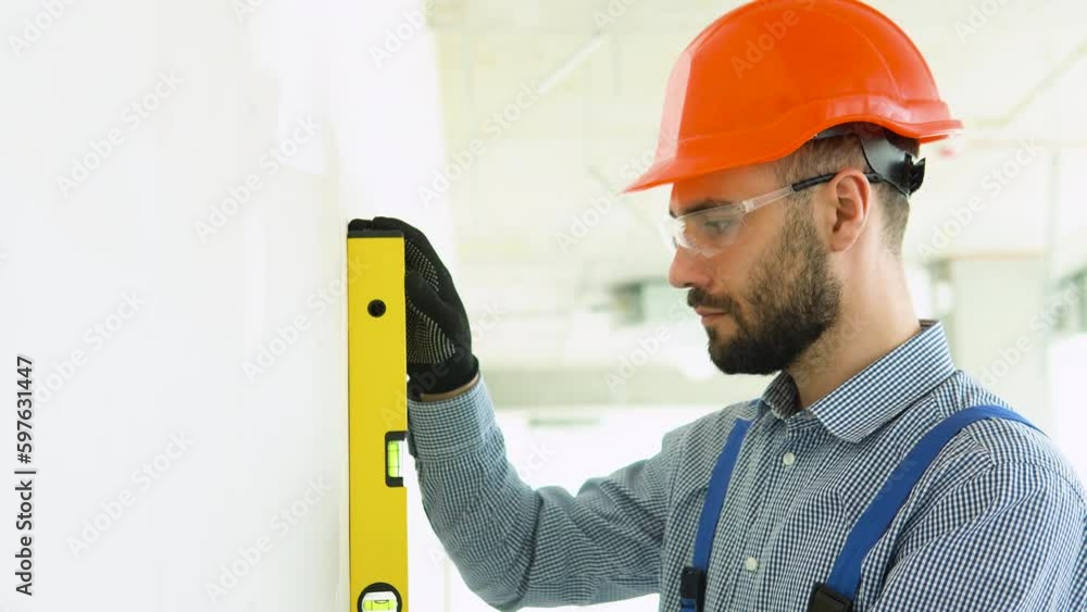 A man builder measures of the vertical deviation of plasterboard wall. Bubble level ruler close up view A man builder measures of the vertical deviation of plasterboard wall. Bubble level ruler close up view