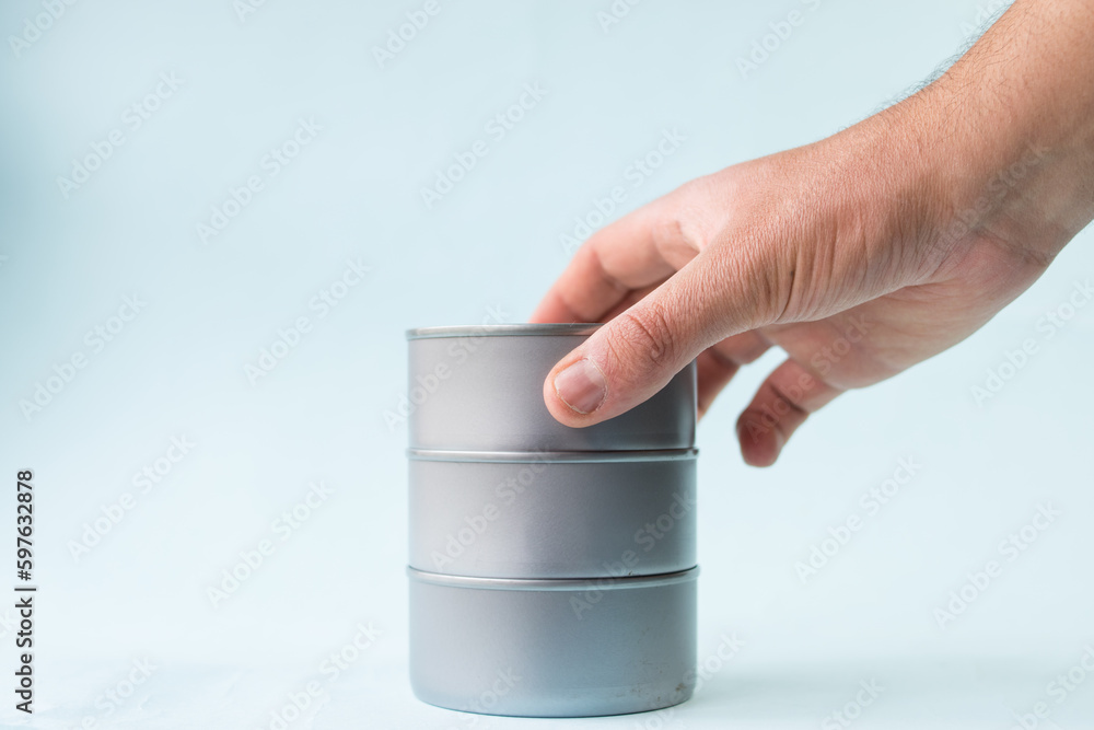 Hand taking food cans on blue background Hand taking food cans on blue background