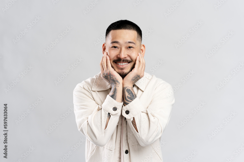 Smiling happy Asian man posing for picture in studio isolated on gray background. Young hipster Smiling happy Asian man posing for picture in studio isolated on gray background. Young hipster