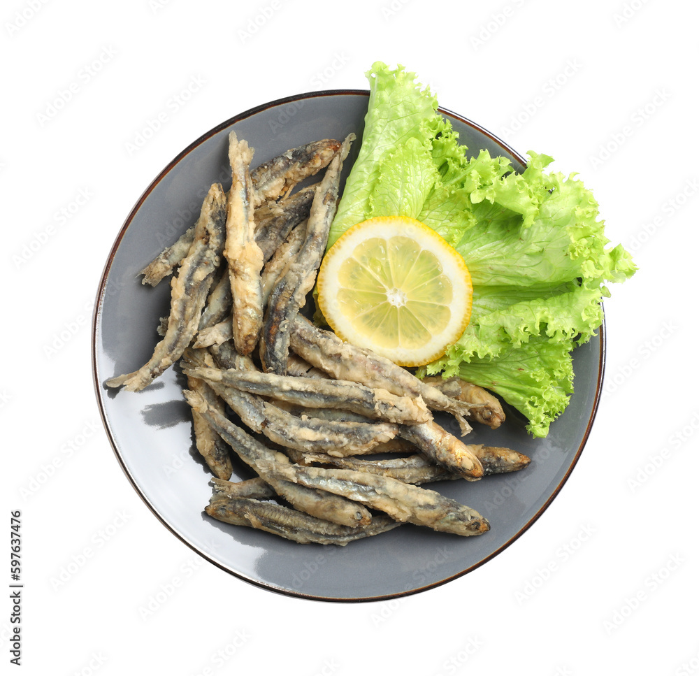 Plate with delicious fried anchovies, lemon and lettuce leaves on white background, top view Plate with delicious fried anchovies, lemon and lettuce leaves on white background, top view