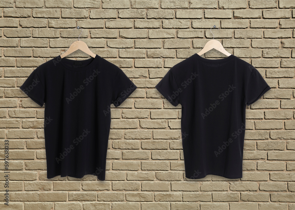 Stylish black t-shirts on beige brick wall, back and front views. Space for design Stylish black t-shirts on beige brick wall, back and front views. Space for design