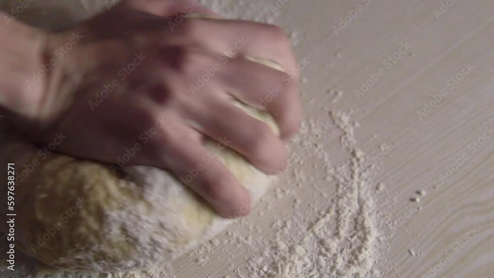 One hand of young woman kneading dough on the table. Mother made bread or pizza at home One hand of young woman kneading dough on the table. Mother made bread or pizza at home