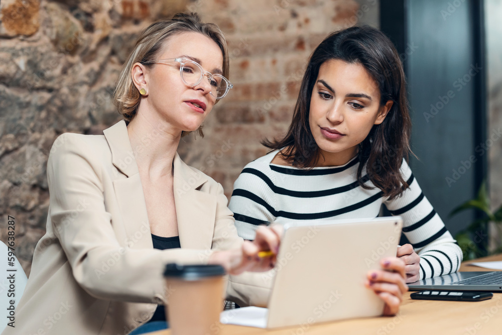Smart group of architects working with laptops and blueprints while talking of their new design business in the office.