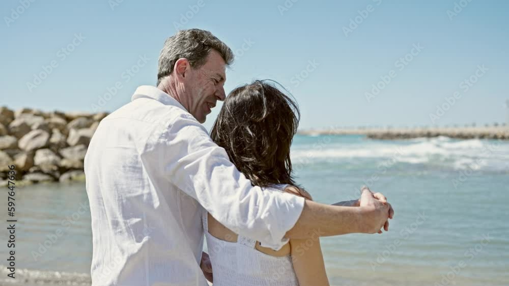Senior man and woman couple hugging each other and kissing at seaside