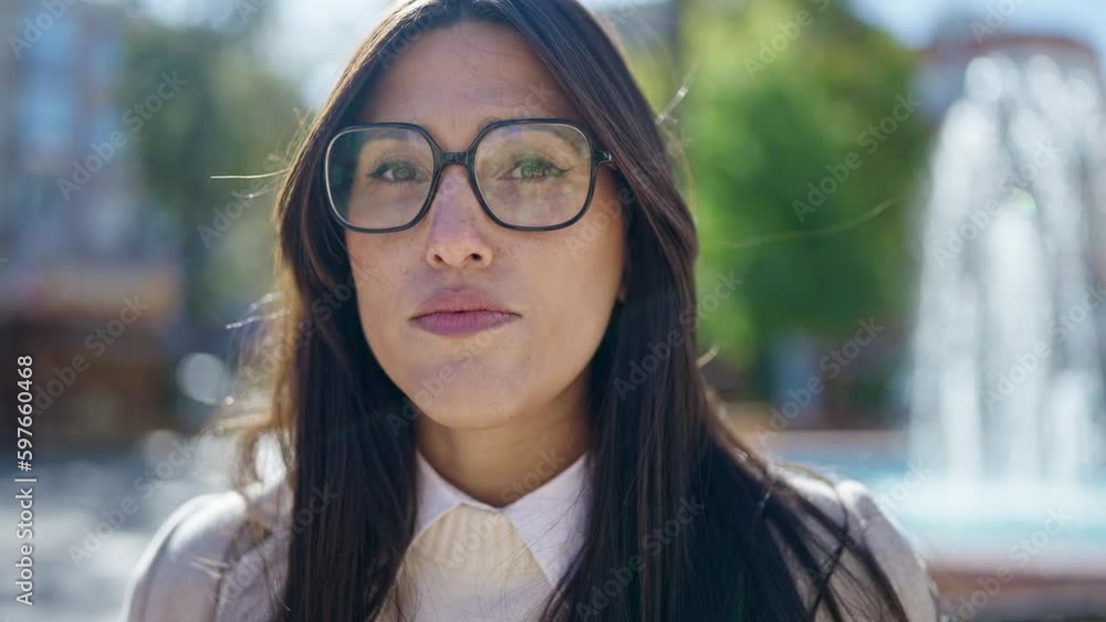 Young beautiful hispanic woman standing with serious expression at park Young beautiful hispanic woman standing with serious expression at park