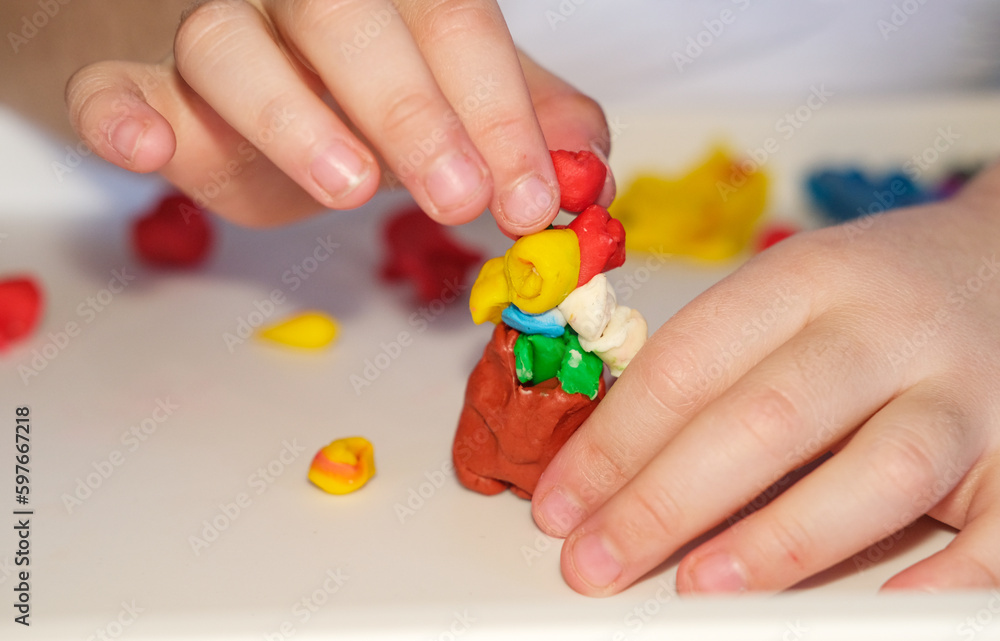 The hand of a child of a girl who sculpts from a light airy multicolored plasticine, a developing activity. the concept of children's creativity and preschool development