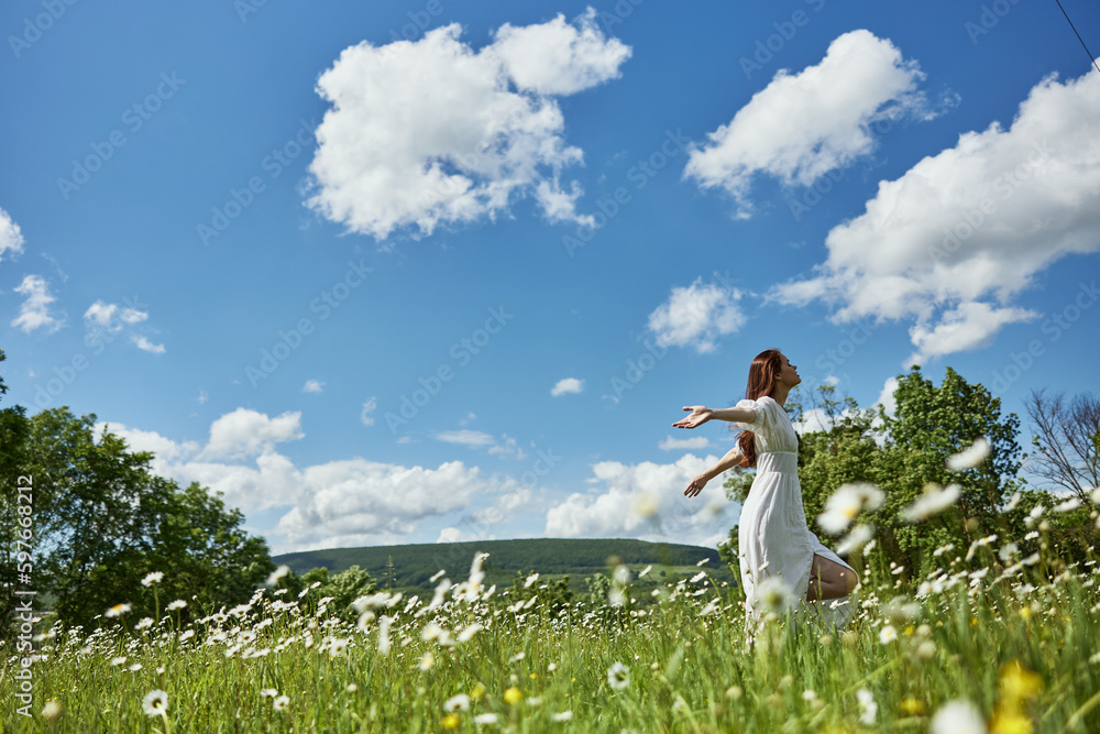 a woman in a light dress runs far across a chamomile field against a blue sky, enjoying harmony with nature a woman in a light dress runs far across a chamomile field against a blue sky, enjoying harmony with nature