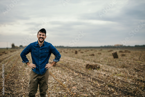 Portrait of a smiling male farmer in working outfit standing in his agricultural land and welcoming and showing his property, Copy space © La Famiglia