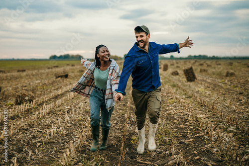 Loving diverse working couple running with arms spread on the countryside field.