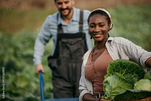 Portrait of two diverse farmers standing in the agricultural field and running their sustainable small business with veggie products.