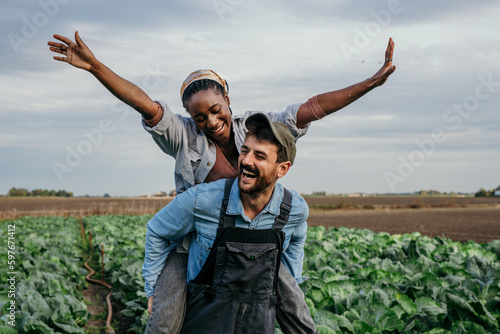 Fotografiet Smiling embraced diverse working couple having a piggyback ride and fun while spending time on their farm together