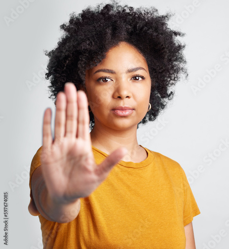 Woman, stop and hand in studio portrait for human rights abuse, racism and afro by gray background. Girl model, gesture or activism for discrimination, justice or protest for freedom, peace or vote photo