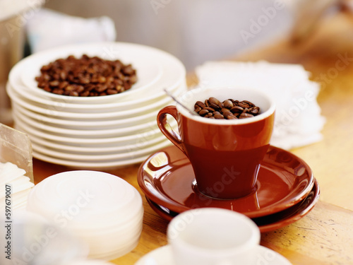 Cup, roasted coffee beans and cafe industry or shop with quality product for marketing or catering. Texture, abstract or background with brown grain as drink, espresso or caffeine ingredient on table