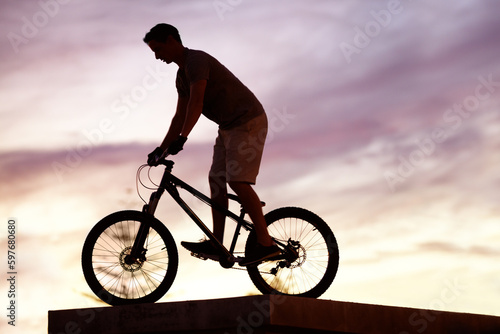 Fototapeta Naklejka Na Ścianę i Meble -  Silhouette, sunset and cycling with man on bicycle for sports, adventure and fitness. Action, exercise and health with male cyclist riding on bmx bike for journey, urban or carbon neutral with mockup