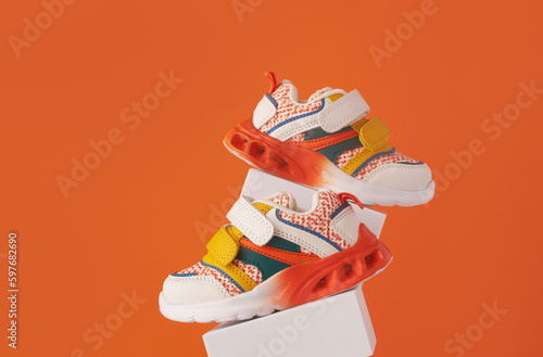 Baby sneakers, child sport shoes pair on color background. Fashion kids outfit. Fashionable sports shoes. Modern minimalistic layout with footwear mock up for your design. Advertising for shoe store