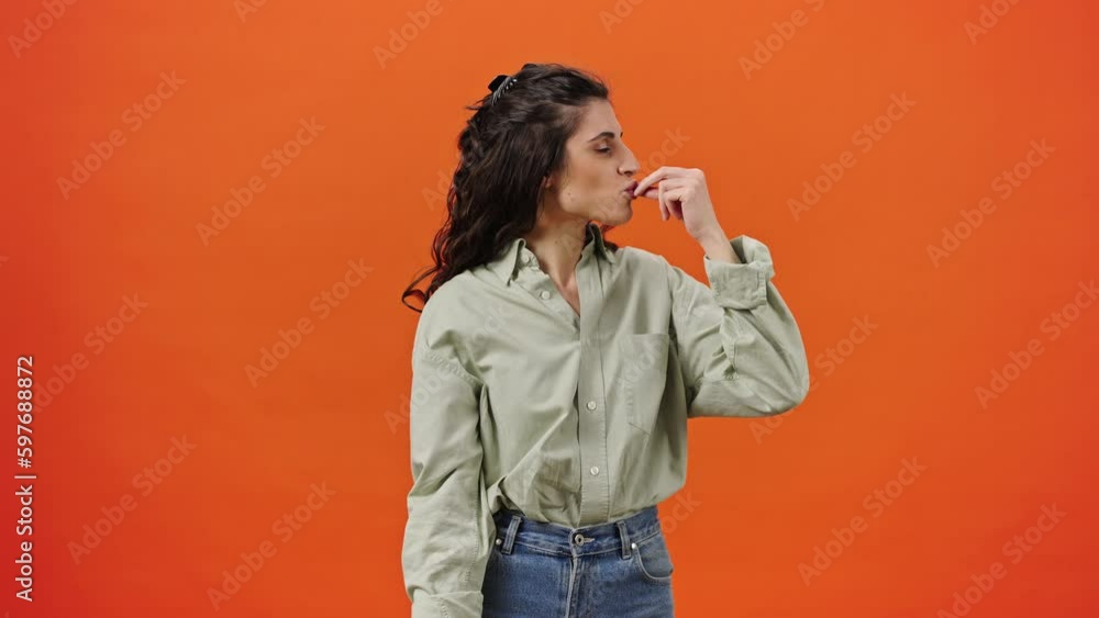 Caucasian emotional woman showing tasty gesture, kisses fingers and says bellissimo, orange backdrop Caucasian emotional woman showing tasty gesture, kisses fingers and says bellissimo, orange backdrop