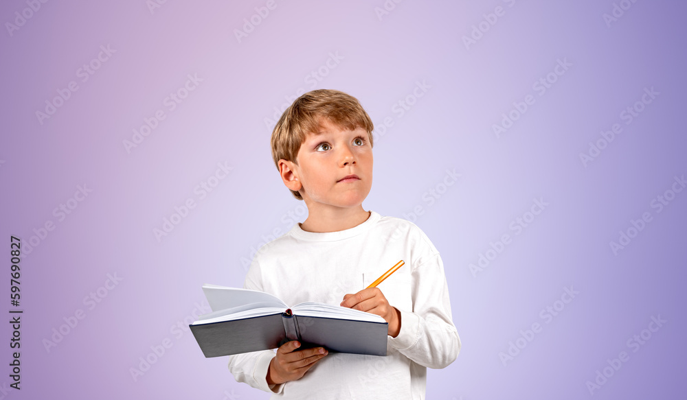 Inspired boy taking notes, looking up portrait on purple backgro Inspired boy taking notes, looking up portrait on purple backgro