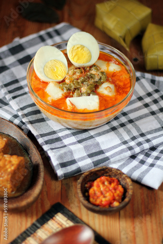 A plate of Indonesian traditional food including a bowl of soup Lontong Sayur