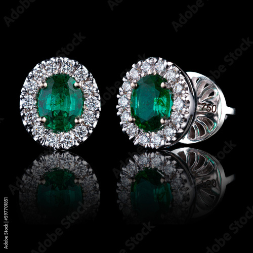 beautiful gold earrings with precious stones diamonds and emeralds on a black background
