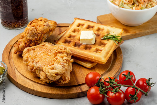 Pieces of fried chicken and waffles on a wooden board, close-up. Traditional American dish.