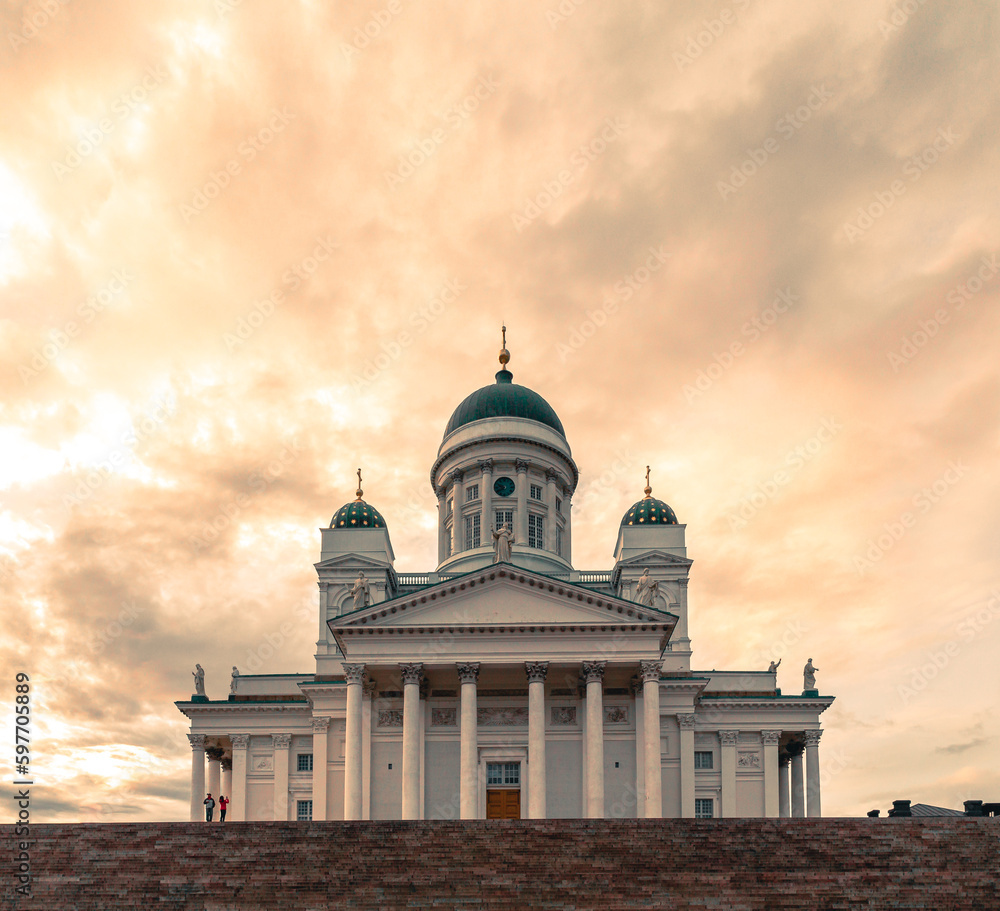Dramatic sky over Helsinki cathedral as two tourists are photographing the church