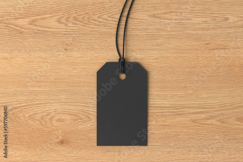 Black tag mockup on wooden background. View directly above