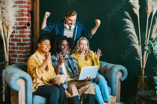 diversity and international group of young people students watching movie on laptop having fun together eating popcorn in college dorm photo