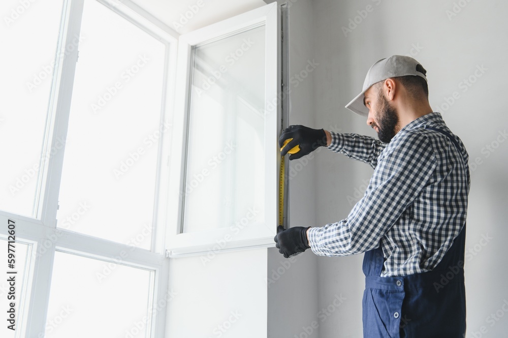 Construction worker installing window in house Construction worker installing window in house
